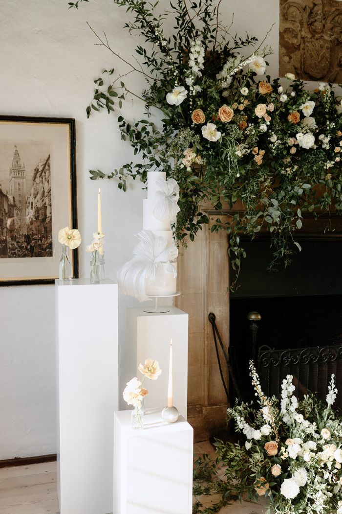 4 tier contemporary white on white wedding cake showcased on and surrounded by pedestals at butley priory