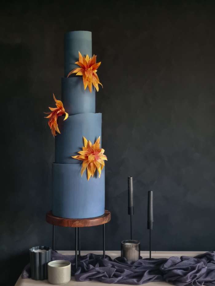 Contemporary tall blue 4 tier wedding cake with striking burnt orange abstract flowers London
