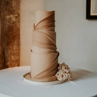 Neutral toned wrap effect wedding cake with fresh sandstorm roses, Butley Priory, Suffolk