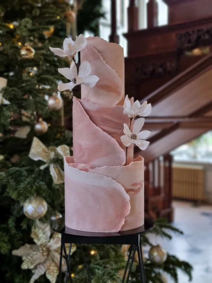 Modern marbled torn fondant wrap effect 3 tier wedding cake with wafer paper magnolia flowers at Gosfield Hall, Essex