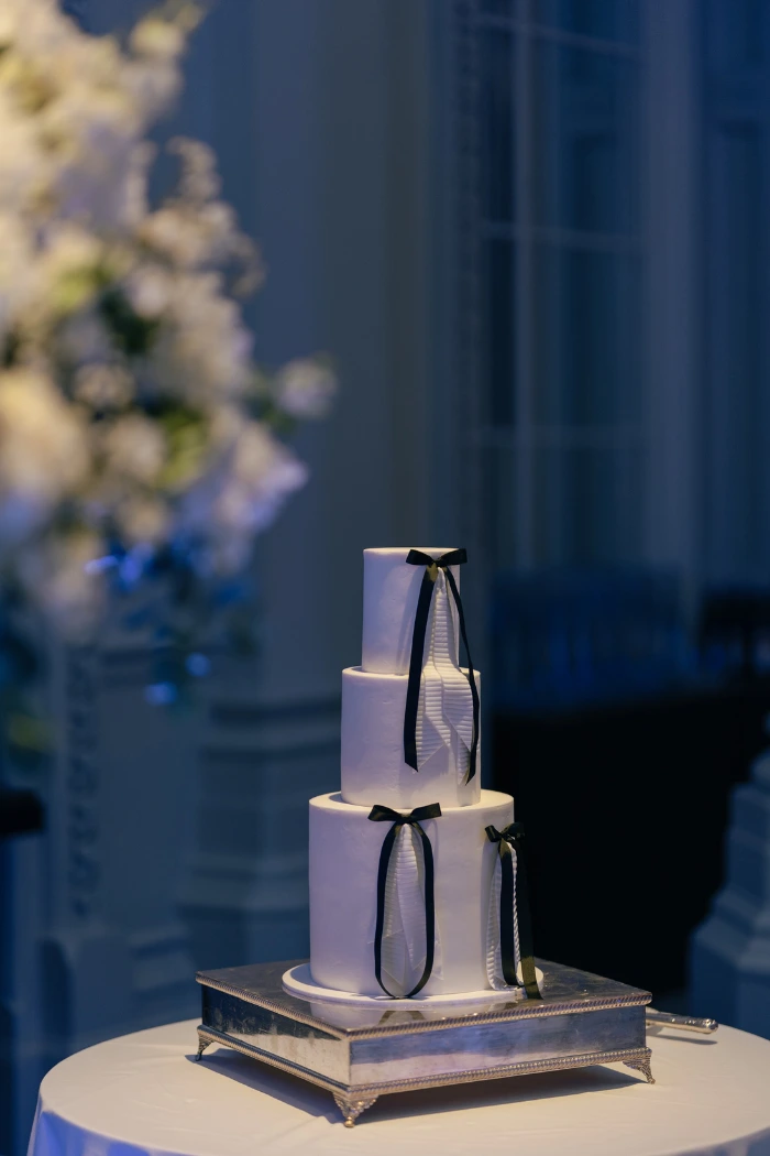 3 tier contemporary white textured wedding cake with white fondant textured ribbons layered with black fabric ribbons at The Langham Hotel London
