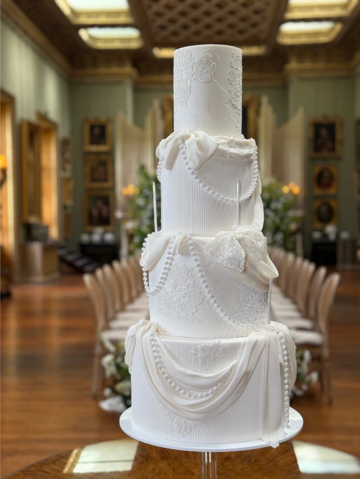 4 tier wedding cake consisting of lace, drapes, pearls, texture and bows at Somerley House, Hampshire