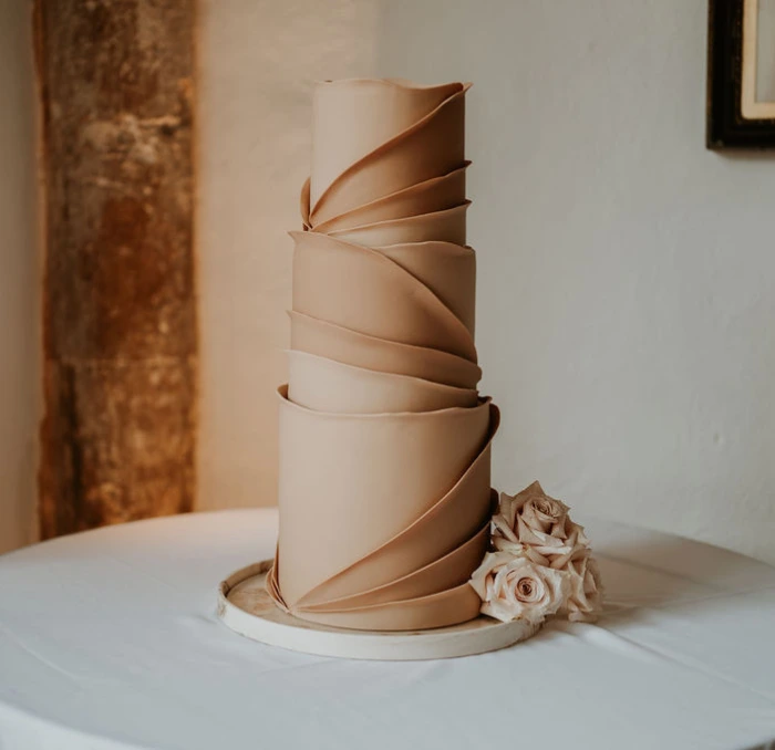 Neutral toned wrap effect wedding cake at Butley Priory, Suffolk
