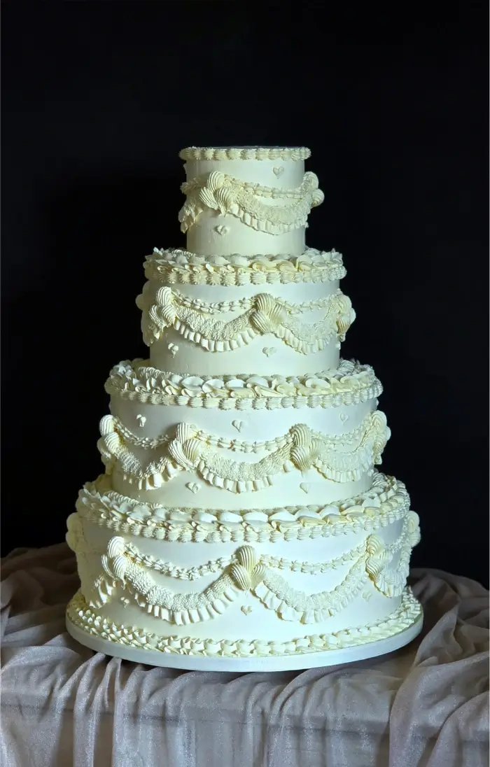 Traditional shallow wide tiered wedding cake with modern vintage piping in ivory tone at Syon Park, London